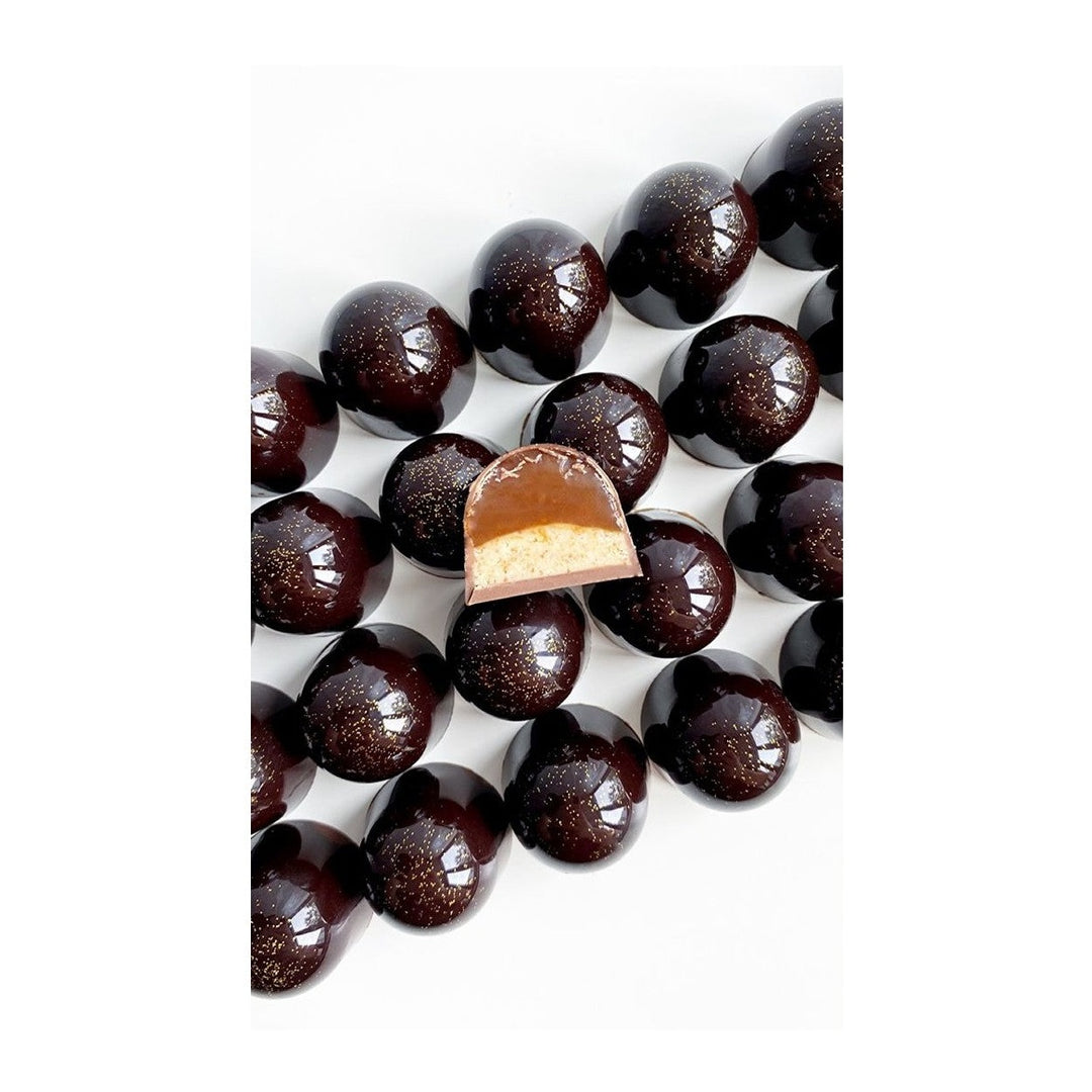 Skåret mørk chokoladepraline med cremet fyld og gyldne glitter