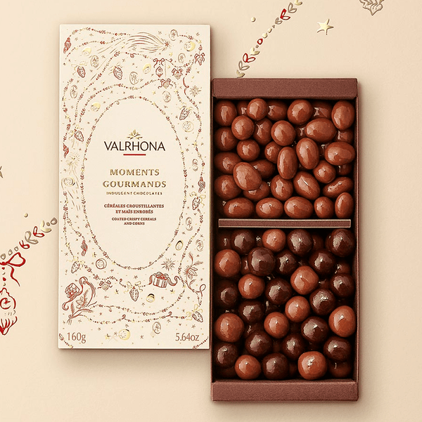 Åben Valrhona Moments Gourmands chokoladeæske med sprøde cerealer og majs i gul og rød juleindpakning
