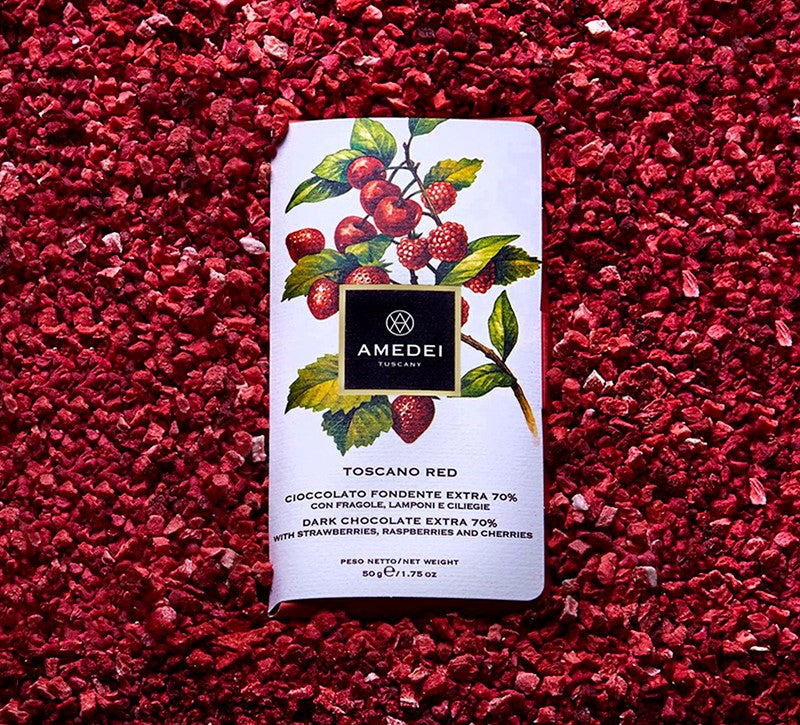 Chokladshopen Amedei Toscano Red mörk choklad 70% med frystorkade jordgubbar, hallon och körsbär på en bädd av bär.