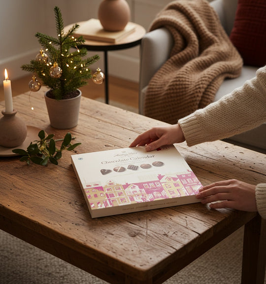 Chokladshopen Anthon Berg chokladkalender med julmotiv på ett rustikt träbord i en mysig julmiljö