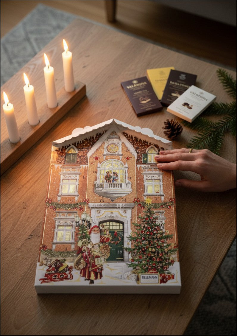 Chokladshopen julkalender format som ett vackert julpyntat hus med mjölkchokladfigurer på ett träbord med ljus.
