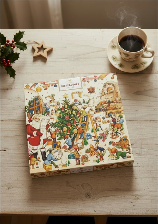 Chokladshopen Niederegger julkalender med marsipan och tomtens verkstad-motiv på ett rustikt träbord med kaffe.