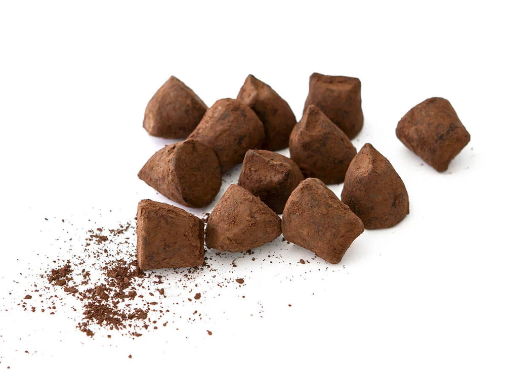 Chokladshopen tryfflar med passionsfrukt pudrade med kakaopulver på vit bakgrund