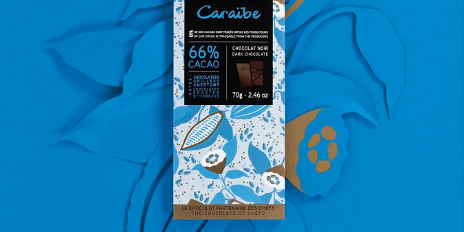 Chokladshopen Valrhona Caraïbe 66% mörk chokladkaka med toner av torkad frukt och vanilj på blå bakgrund.